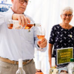 Ein Winzer schenkt Rosewein aus der Flasche in ein Glas.