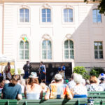 Publikum auf Bänken sitzend vor dem Schloss Branitz schauen auf eine Bühne