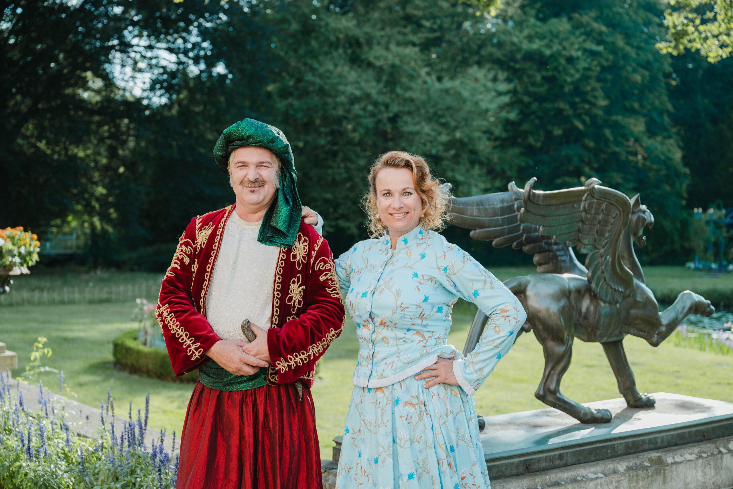 Zwei als Fürst und Fürstin gekleidete Personen stehen auf der Schlossterrasse. Im Hintergrund ist die Zinkgussplastik eines Greifen zu sehen